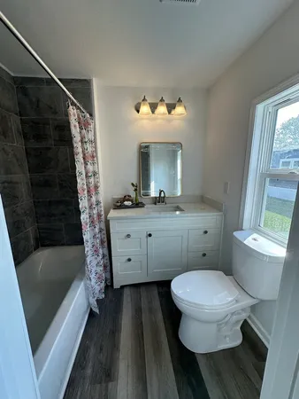 a bathroom with a sink a toilet a mirror a vanity and bathtub