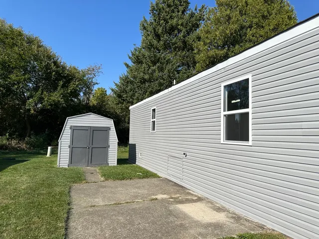 a view of a white house with a small yard and a large tree