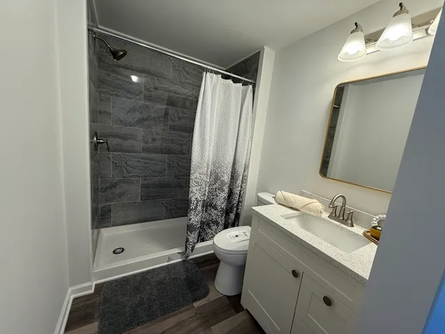 a bathroom with a bathtub shower sink vanity and toilet