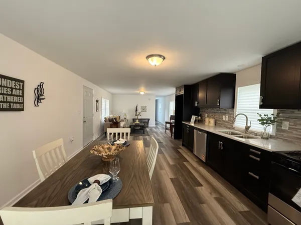 a living room with stainless steel appliances kitchen island granite countertop a sink dishwasher a stove and a microwave oven with wooden floor