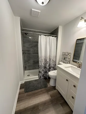a bathroom with a granite countertop sink a toilet and shower