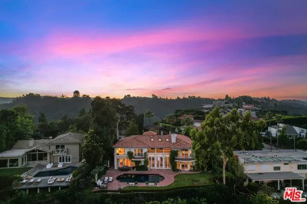 a front view of a house with a garden and lake view
