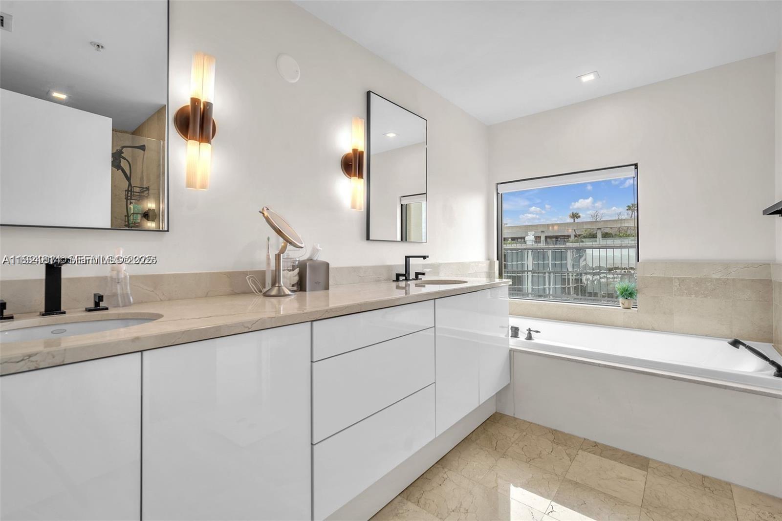 3400 Southwest 27th Avenue, Unit 1105 Miami, FL 33133 - Photo 13 of 24 a bathroom with a sink a large mirror and a bathtub
