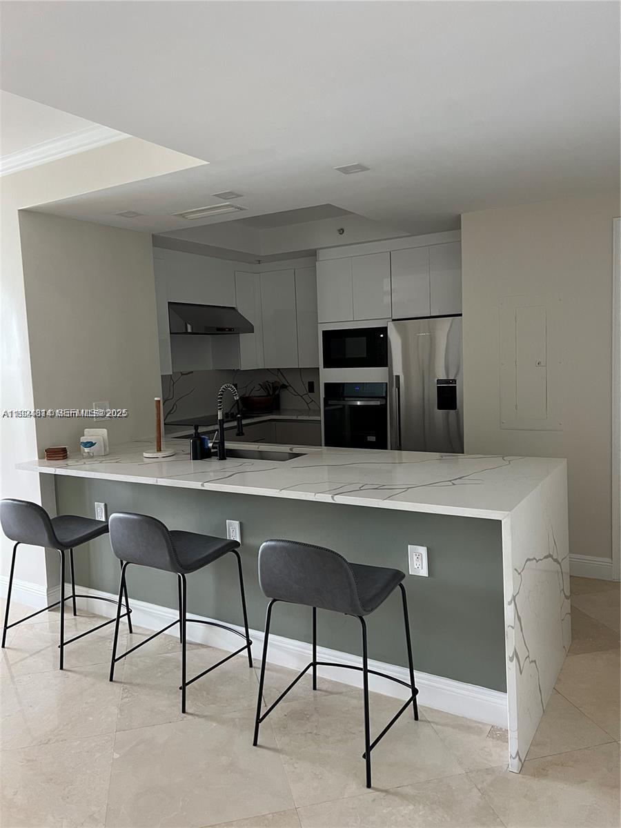 3400 Southwest 27th Avenue, Unit 1105 Miami, FL 33133 - Photo 8 of 24 a kitchen with stainless steel appliances a dining table chairs microwave and sink