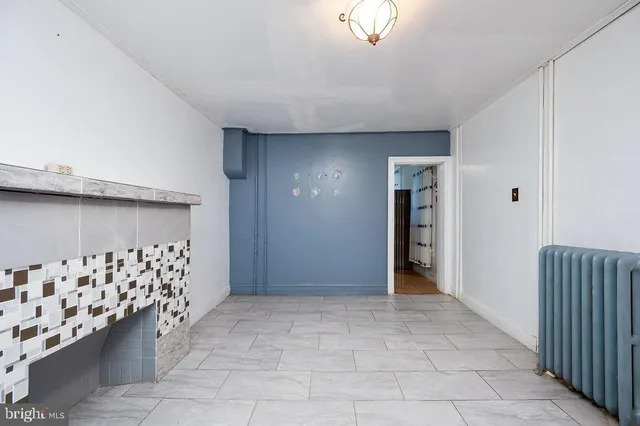 a view of an empty room with wooden floor and a fireplace