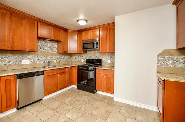 a kitchen with stainless steel appliances granite countertop a stove a sink a refrigerator and a microwave