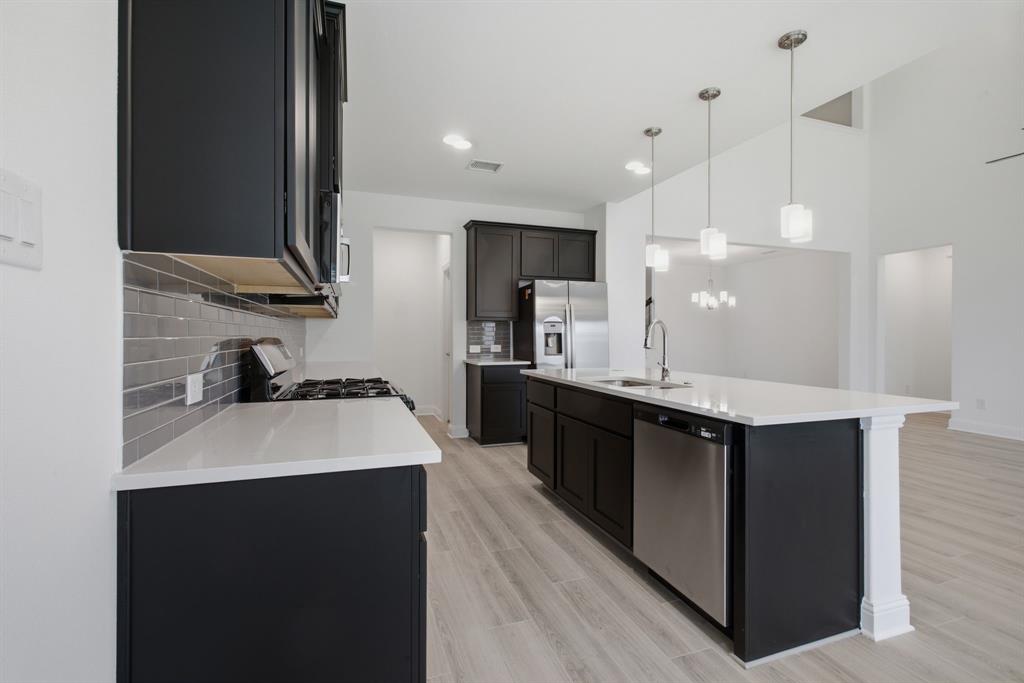2911 Hanscom Street Forney, TX 75126 - Photo 23 of 40 Modern kitchen featuring dark cabinetry, light countertops, subway tile backsplash, and stainless steel appliances