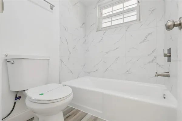 a bathroom with a white toilet sitting next to a white tub