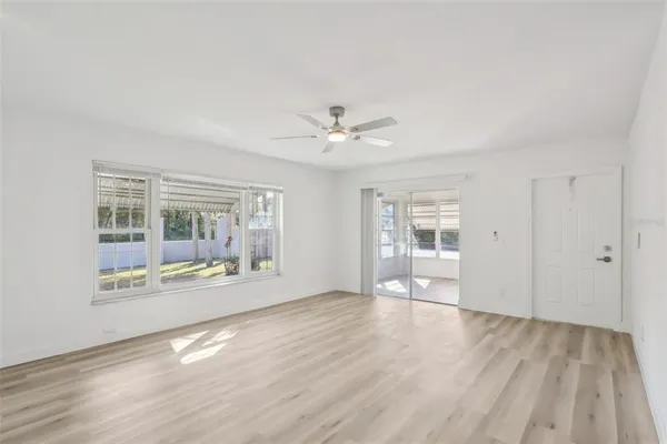 a view of an empty room with wooden floor and a window