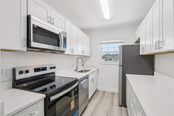 a kitchen with stainless steel appliances a stove microwave and sink