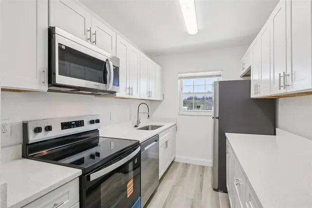 a kitchen with stainless steel appliances a stove microwave and sink