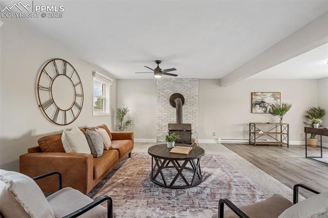 15535 Softwood Road Elbert, CO 80106 - Photo 26 of 47 Living room featuring a wood stove, ceiling fan, and light wood-style flooring