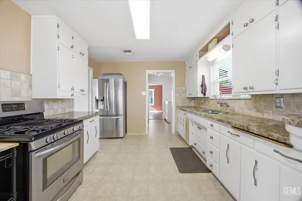 a kitchen with granite countertop a sink stove and refrigerator