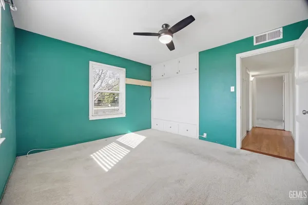 a view of an empty room with a window and a ceiling fan