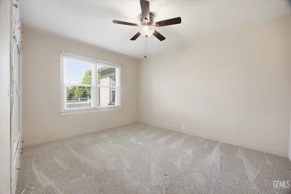 an empty room with windows and fan