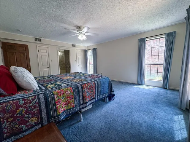 a spacious bedroom with a bed a dresser and a window