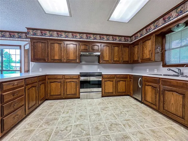 a kitchen with stainless steel appliances granite countertop a stove a sink dishwasher and a refrigerator