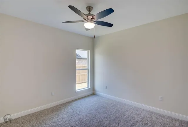 an empty room with windows and ceiling fan