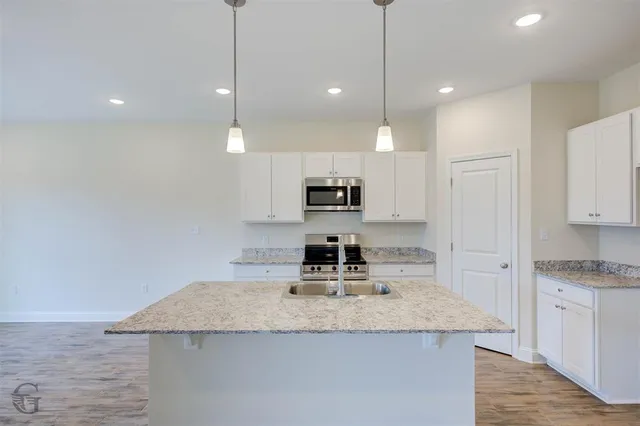 a kitchen with kitchen island granite countertop a sink a counter top space and stainless steel appliances