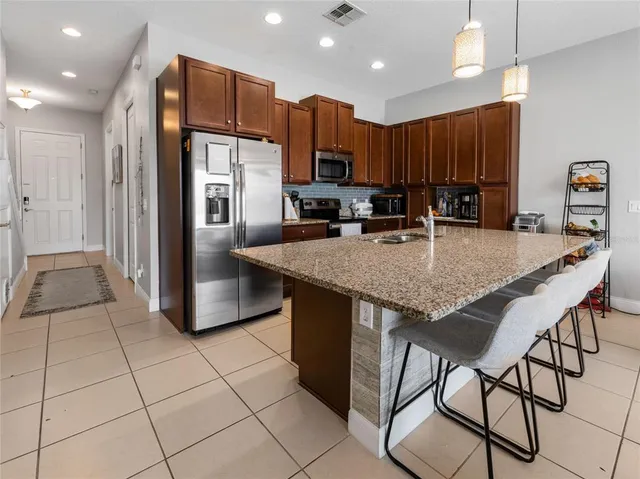 a kitchen with stainless steel appliances granite countertop a stove a refrigerator a sink a oven with a dining table and chairs