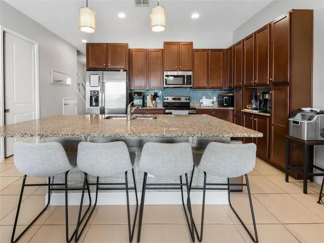 a kitchen with stainless steel appliances granite countertop a table chairs sink and cabinets