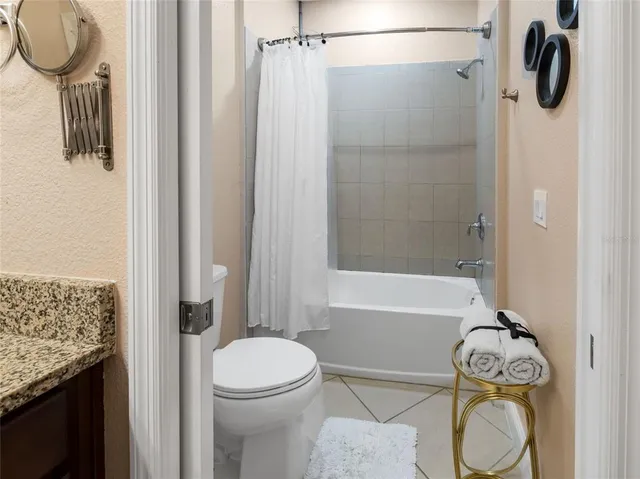 a bathroom with a granite countertop bathtub shower sink vanity and toilet