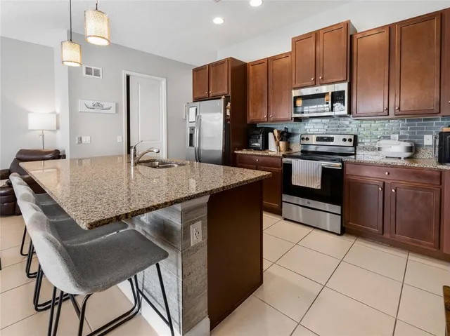 a kitchen with kitchen island granite countertop a table chairs microwave and refrigerator