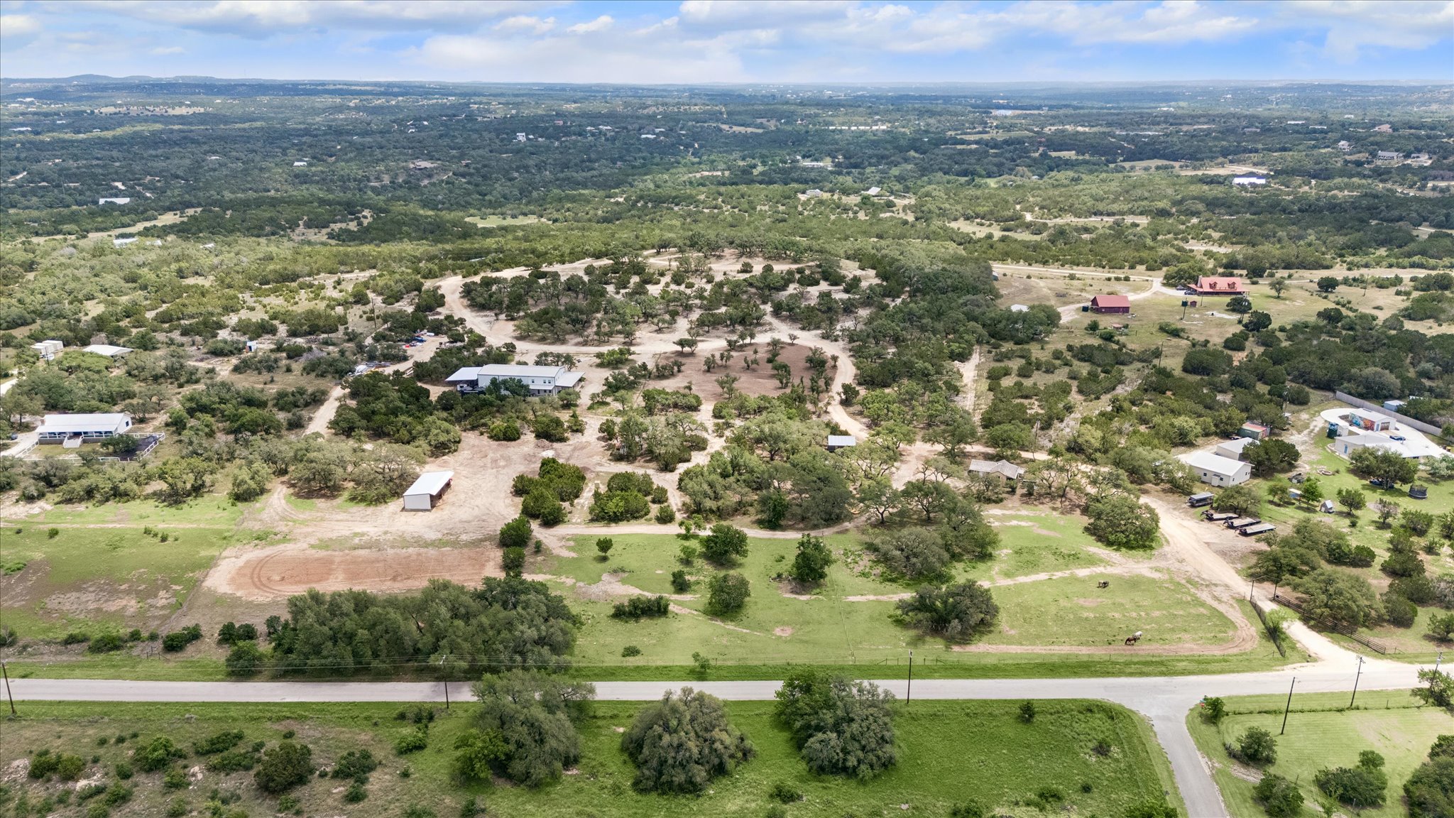 6411 West Fitzhugh Road Dripping Springs, TX 78620 - Photo 4 of 34 Expansive property featuring a paved road frontage, natural tree coverage, scattered residential structures, and a large barn structure