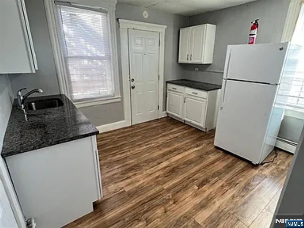 489 Market Street, Unit 2 Paterson, NJ 07501 - Photo 3 of 6 a kitchen with granite countertop a refrigerator a stove a sink and white cabinets with wooden floor