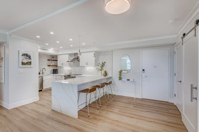 a large white kitchen with wooden floor and stainless steel appliances
