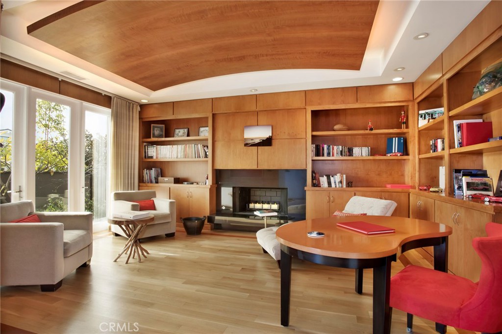 Relax by the fireplace in this showpiece library that is filled with natural light and a curved wooden ceiling.