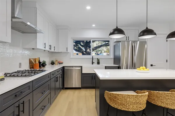 a kitchen with stainless steel appliances granite countertop a sink dishwasher a stove a microwave oven a refrigerator with white cabinets and wooden floor