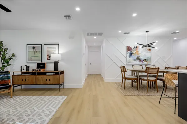 a living room with furniture a rug kitchen view and a table