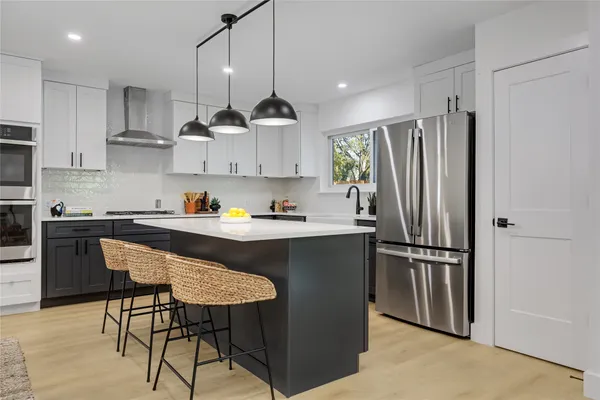a kitchen with stainless steel appliances granite countertop a refrigerator a sink dishwasher a stove and a refrigerator with wooden floor
