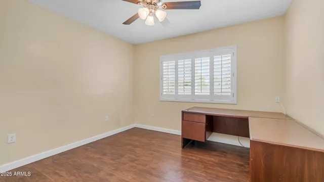 an empty room with wooden floor fan and windows