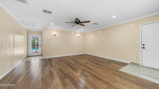 an empty room with wooden floor and ceiling fan