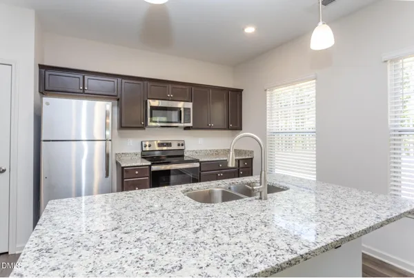 a kitchen with stainless steel appliances granite countertop a sink refrigerator and microwave
