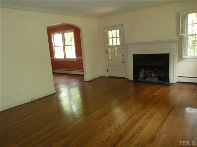 1612 Jarvis Street Raleigh, NC 27608 - Photo 3 of 25 an empty room with wooden floor fireplace and windows