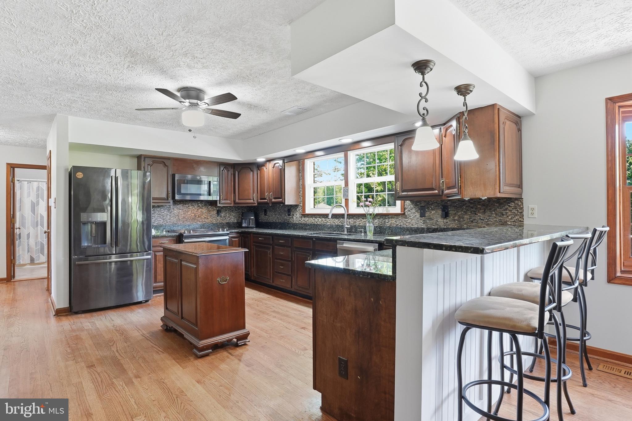 6118 Fishers Station Road Lothian, MD 20711 - Photo 9 of 62 a kitchen with stainless steel appliances granite countertop a refrigerator a stove a sink dishwasher a dining table and chairs with wooden floor