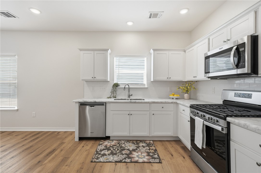 124 Lavaca Rockport, TX 78382 - Photo 12 of 39 a kitchen with stainless steel appliances granite countertop a sink stove and microwave