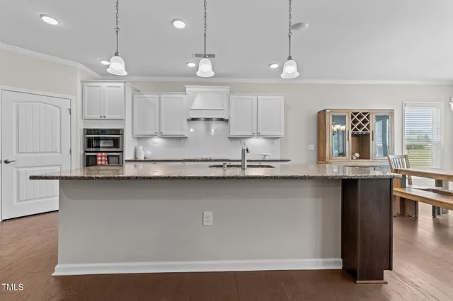 a kitchen with stainless steel appliances granite countertop a sink a stove and a wooden floors