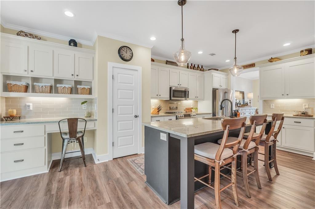 230 Alcovy Reserve Way Covington, GA 30014 - Photo 24 of 53 a kitchen with stainless steel appliances kitchen island granite countertop a wooden floor and white cabinets