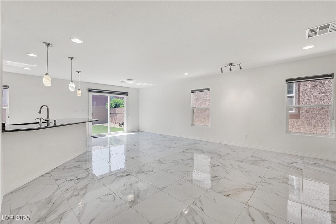 Unfurnished living room with recessed lighting, baseboards, a sink, and light marble finish floors
