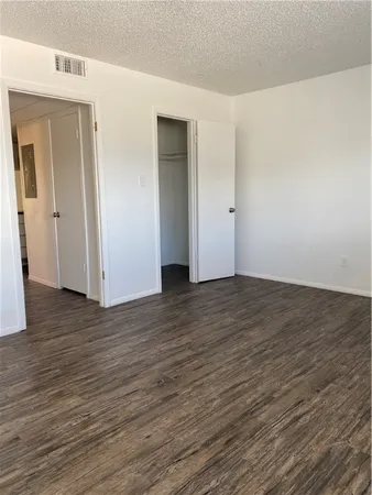 a view of an empty room with wooden floor and closet