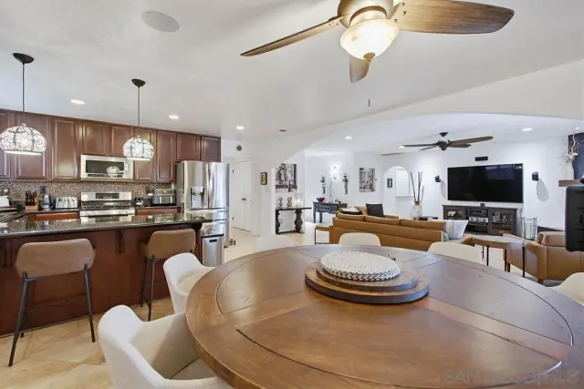 a kitchen with stainless steel appliances granite countertop a refrigerator a stove a sink dishwasher a dining table and chairs with wooden floor