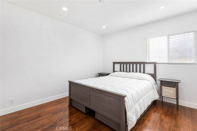 a large bed sitting in a bedroom next to a window with wooden floor