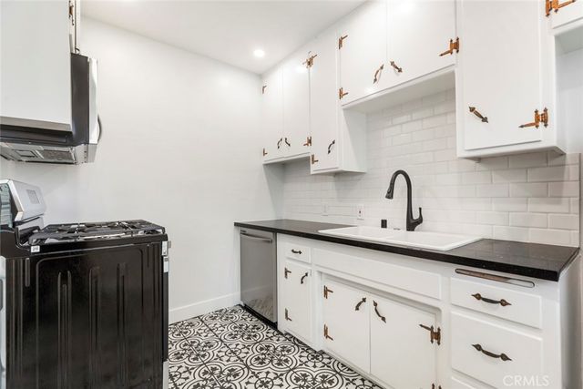a kitchen with granite countertop a sink a stove and cabinets