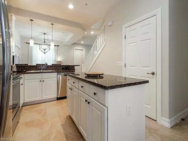 a kitchen with granite countertop a sink cabinets and stainless steel appliances