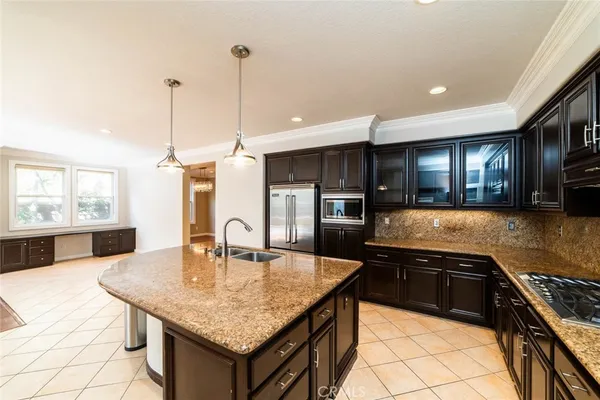 a kitchen with stainless steel appliances granite countertop a sink a stove and a wooden cabinets
