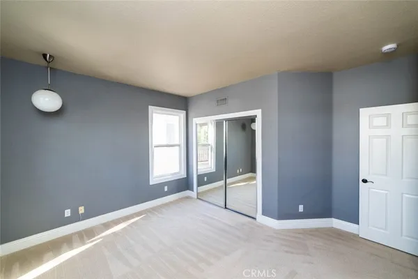 a view of an empty room with window and wooden floor